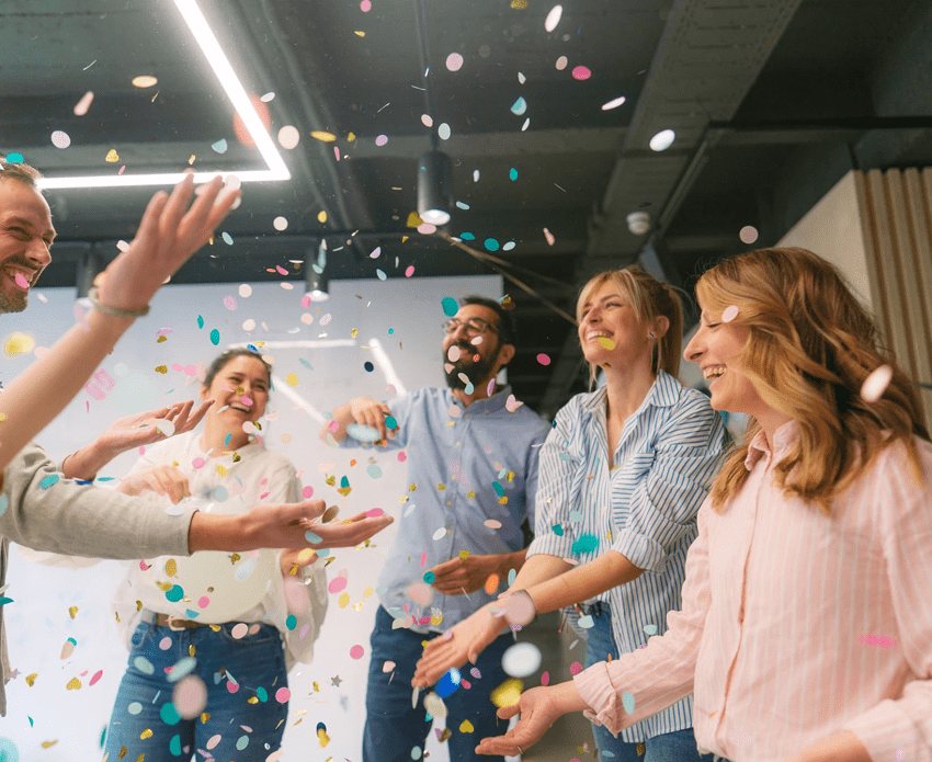 People celebrating with colorful confetti indoors.