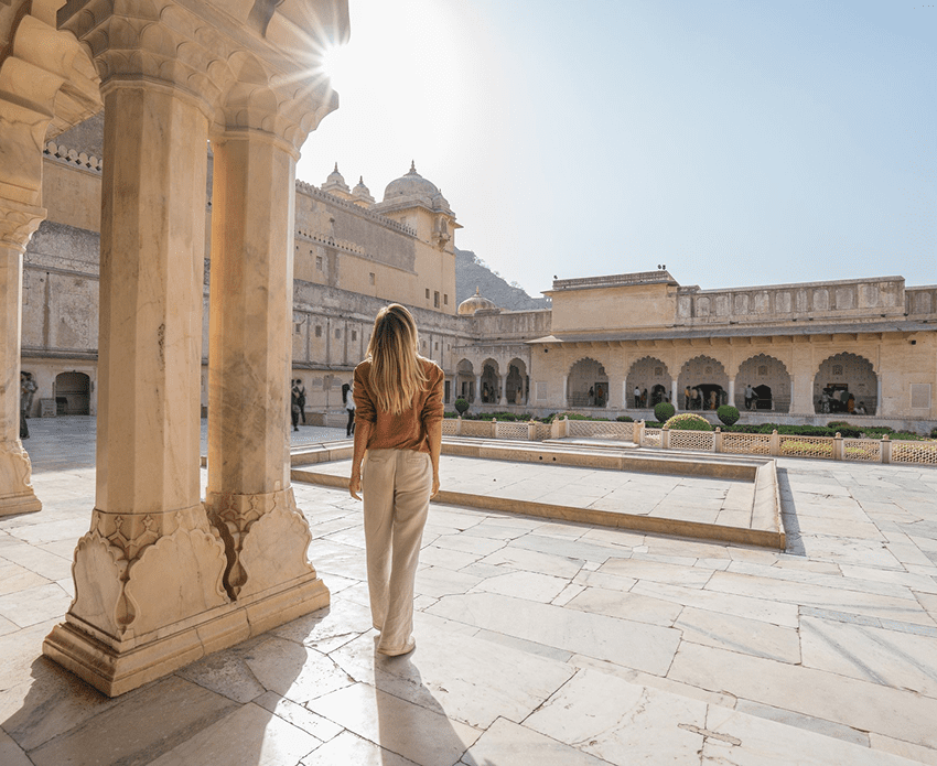 Woman standing in historic courtyard, sunlight streaming.
