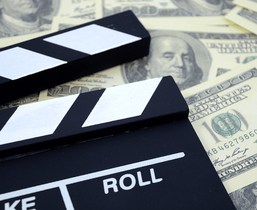 Clapperboard on hundred-dollar bills background.