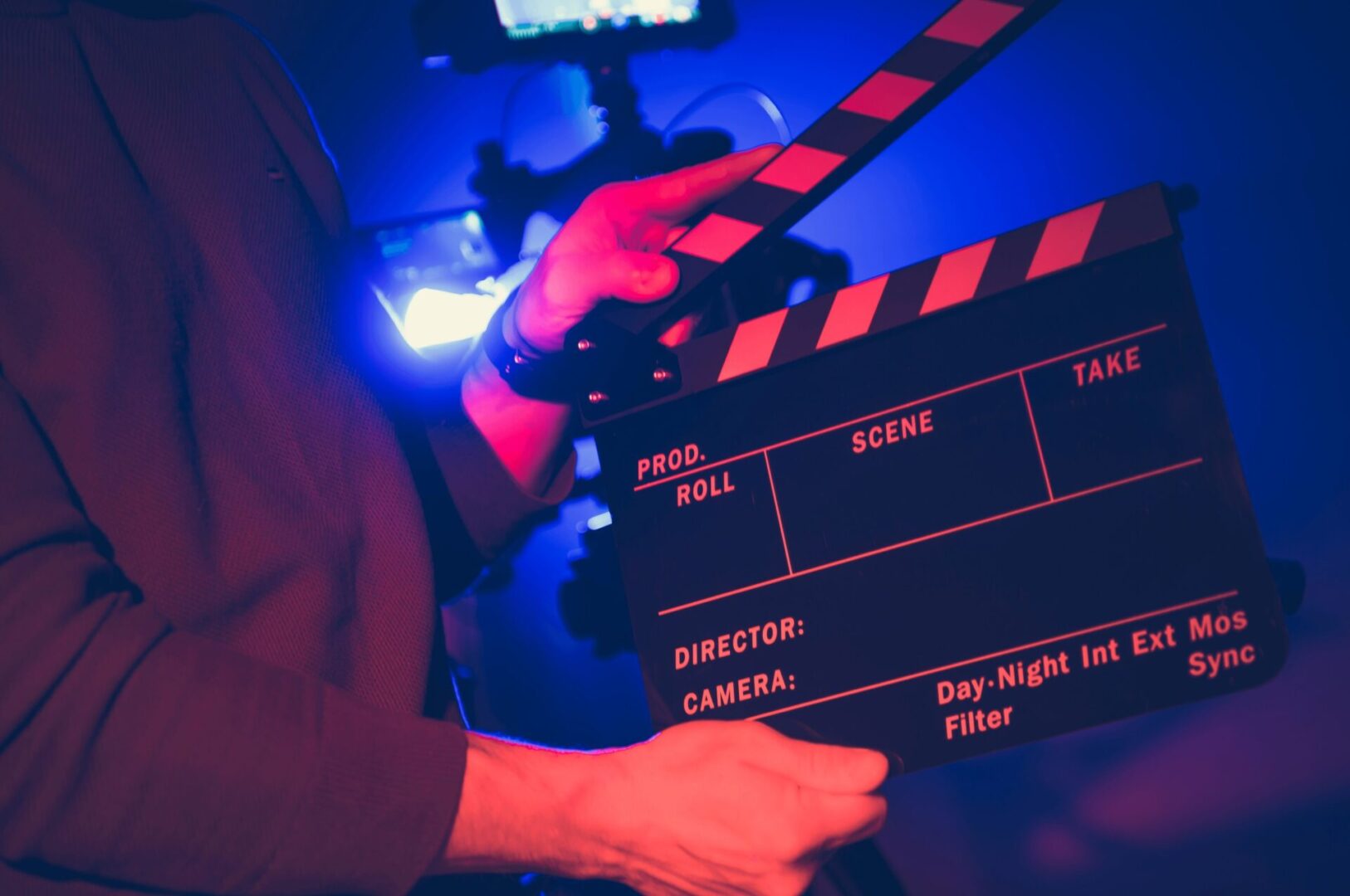 Person holding a movie clapperboard on set.
