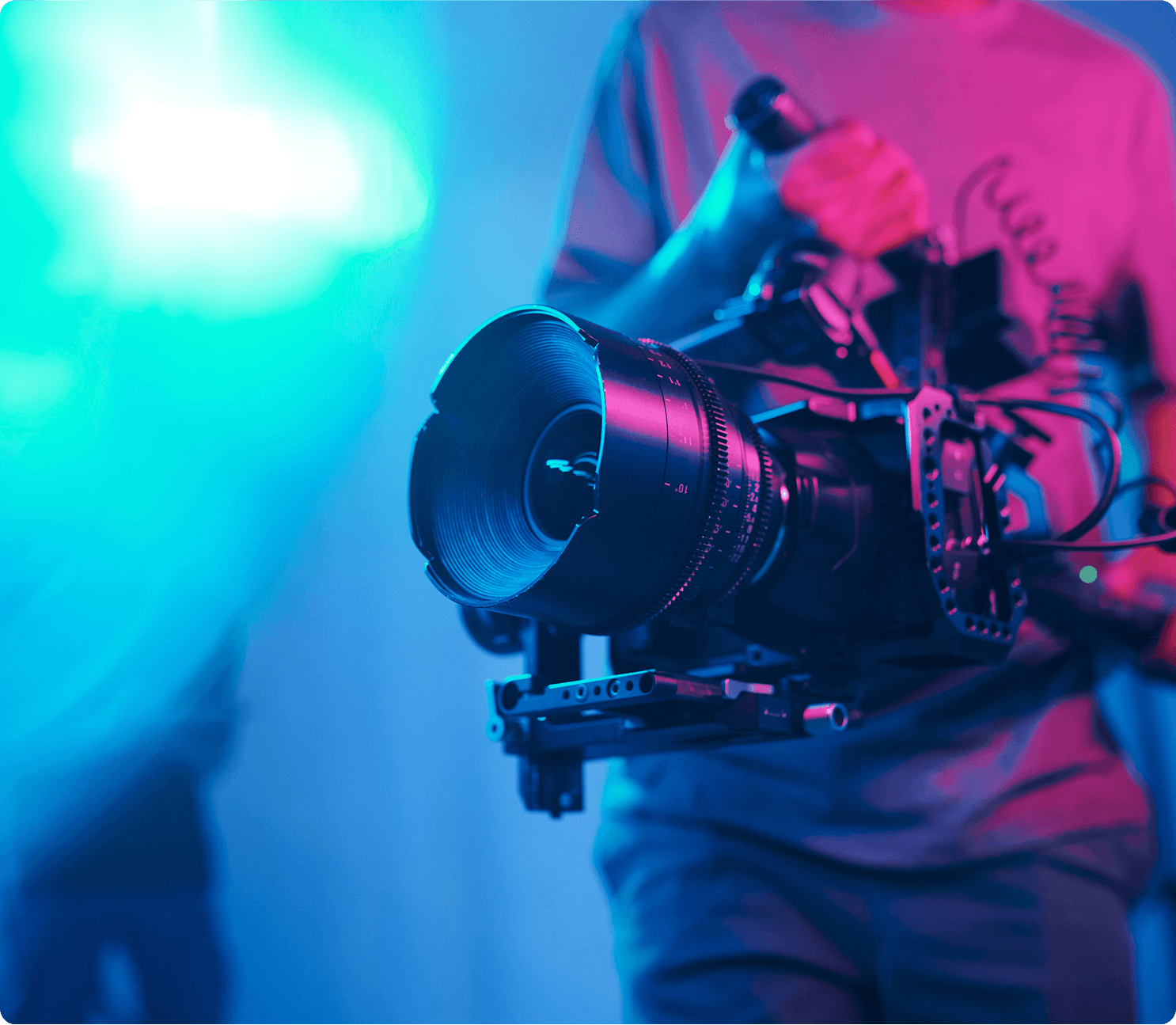Person holding professional video camera, blue lighting.